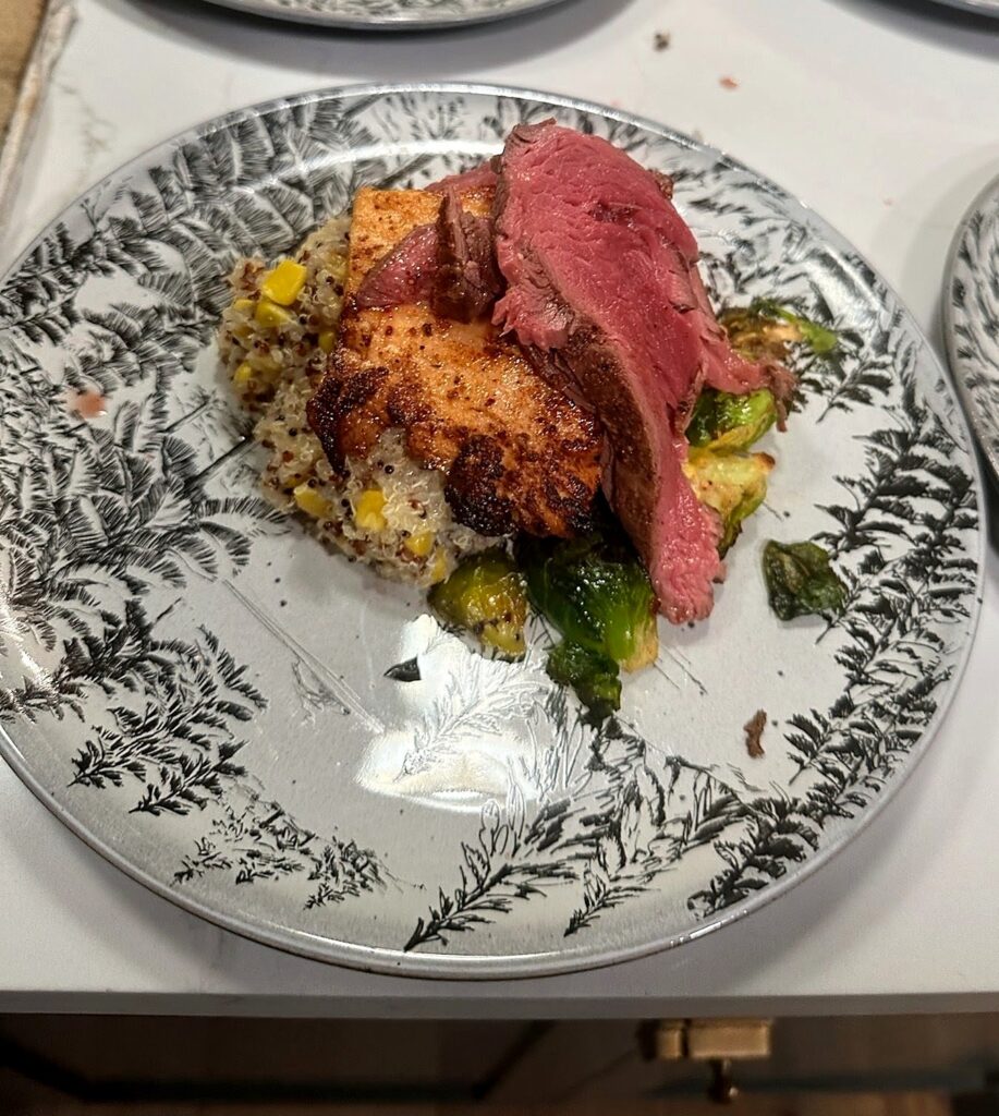 Sliced beef and seared chicken over quinoa with charred brussels sprouts