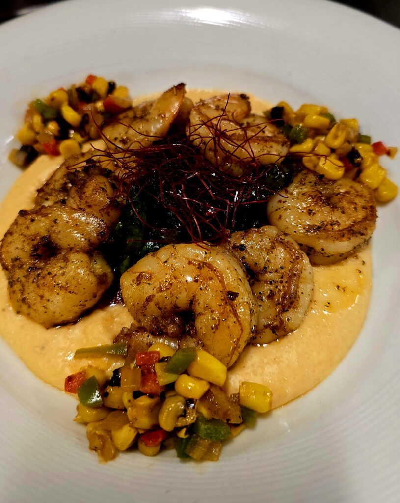 Blackened shrimp over creamy grits with charred corn and pepper succotash