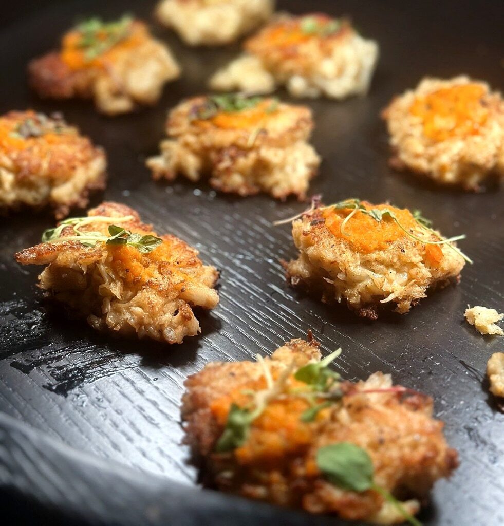 Crab cake appetizers topped with pepper aioli and micro greens