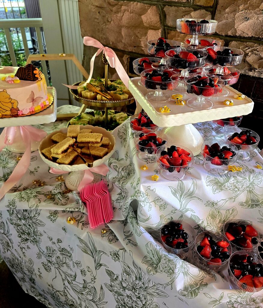 Dessert and tea sandwich table catered for a birthday party, with fruit cups and a custom cake