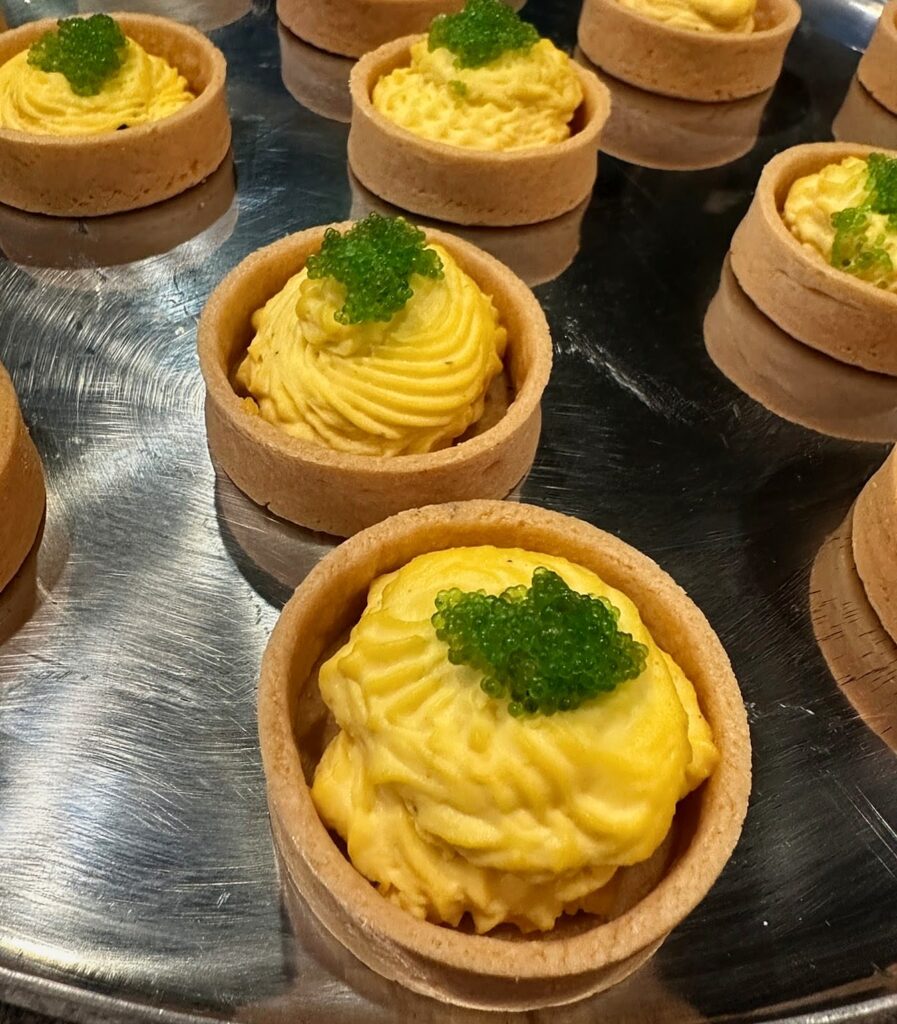 Egg yolk mousse tartlets topped with wasabi tobiko, a passed appetizer for private events