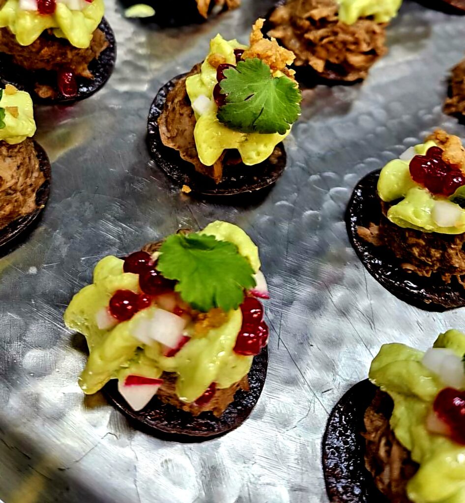 Mole pork tostada bites with avocado mousse, prickly pear pearls, radish and cilantro, passed as catered appetizers