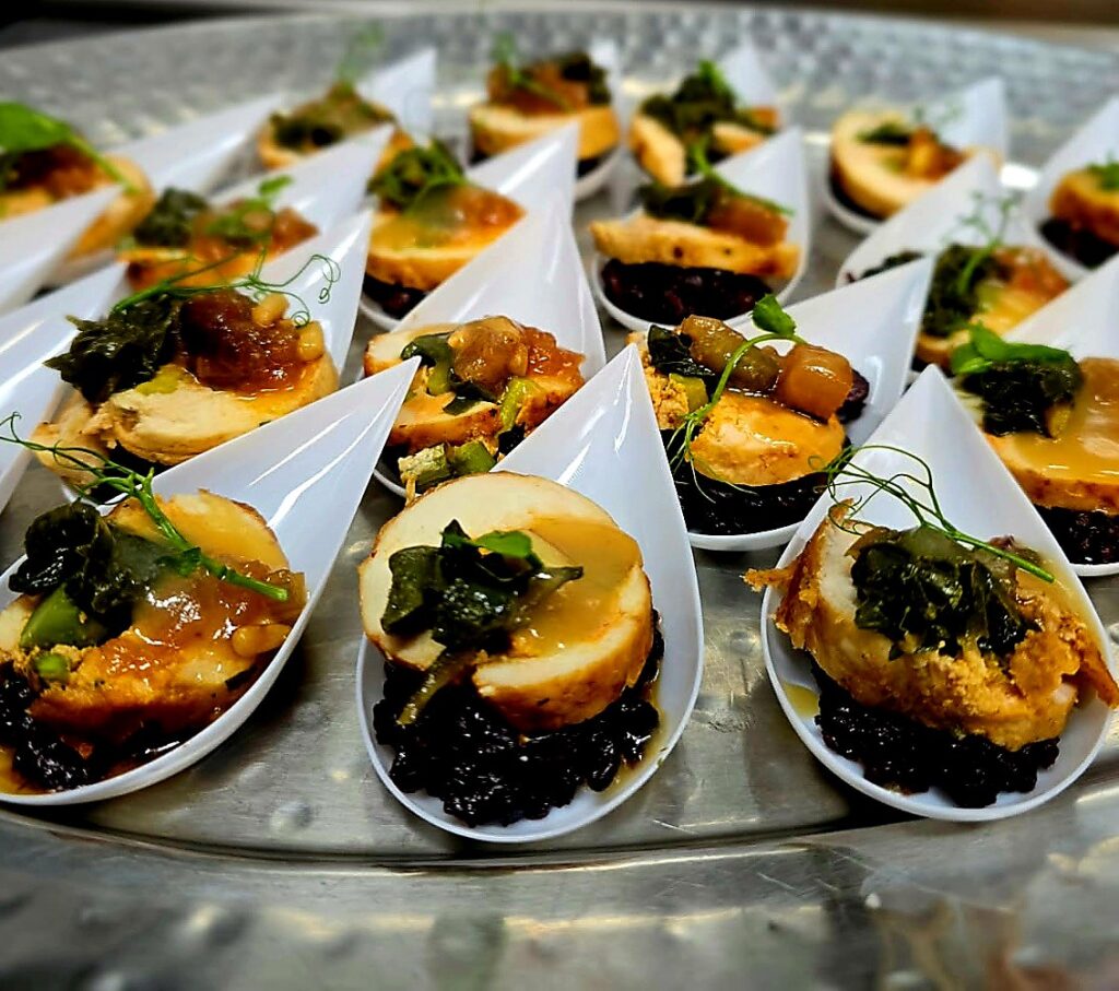 Passed appetizer spoons with sliced chicken, black rice and chutney at a catered event