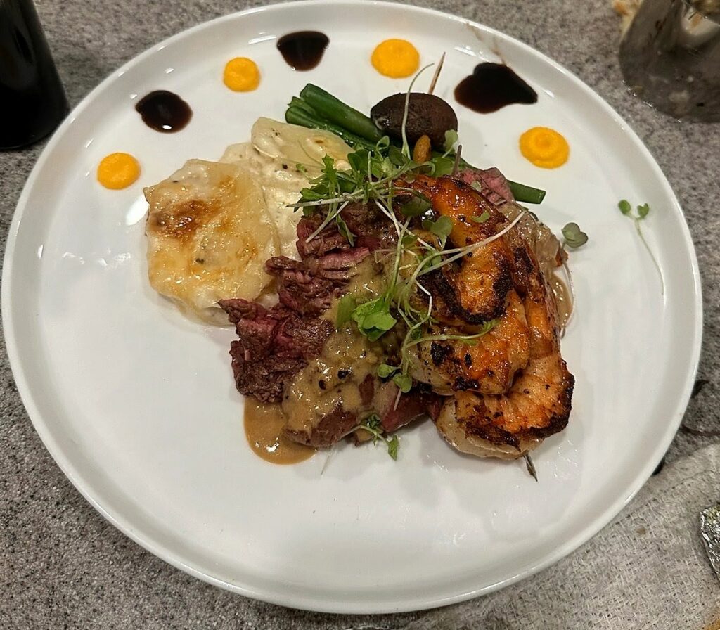 Steak and grilled shrimp with potato gratin, green beans and carrot puree, plated by a Denver private chef