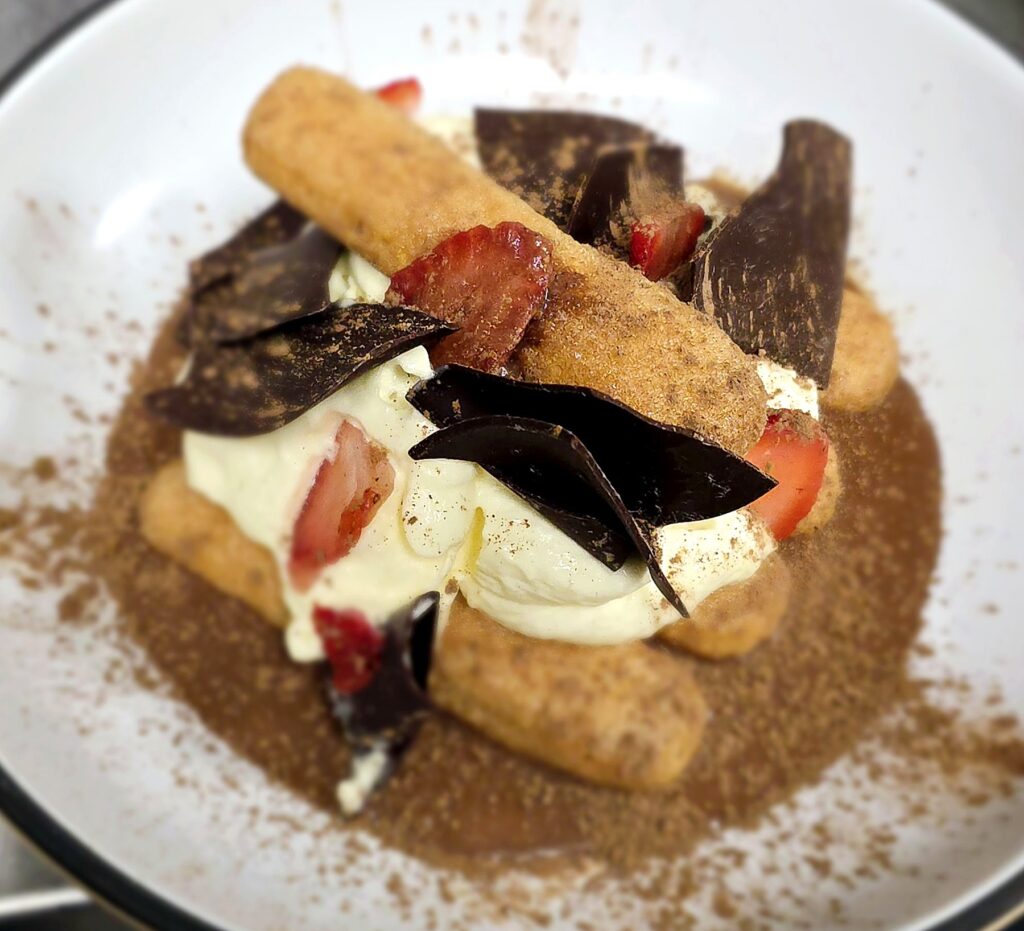 Tiramisu with strawberries, dark chocolate shards and cocoa, served at a private dinner