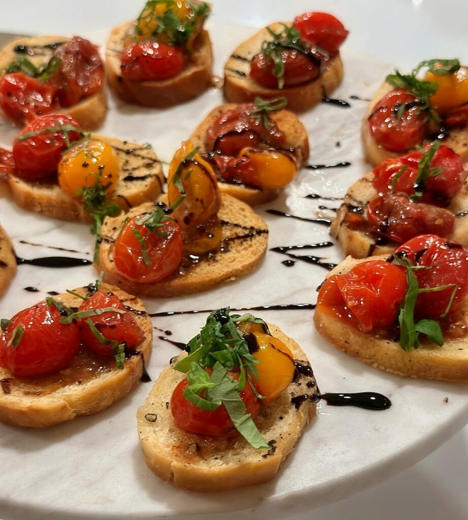 Blistered tomato bruschetta with basil and balsamic glaze, passed at a catered event